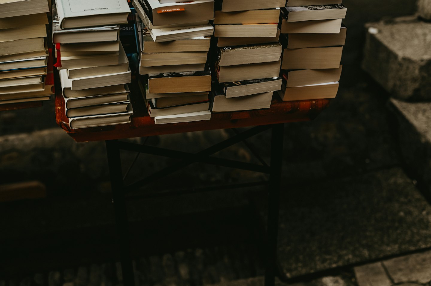 Stapel von Büchern auf einem dunkelroten Tisch.